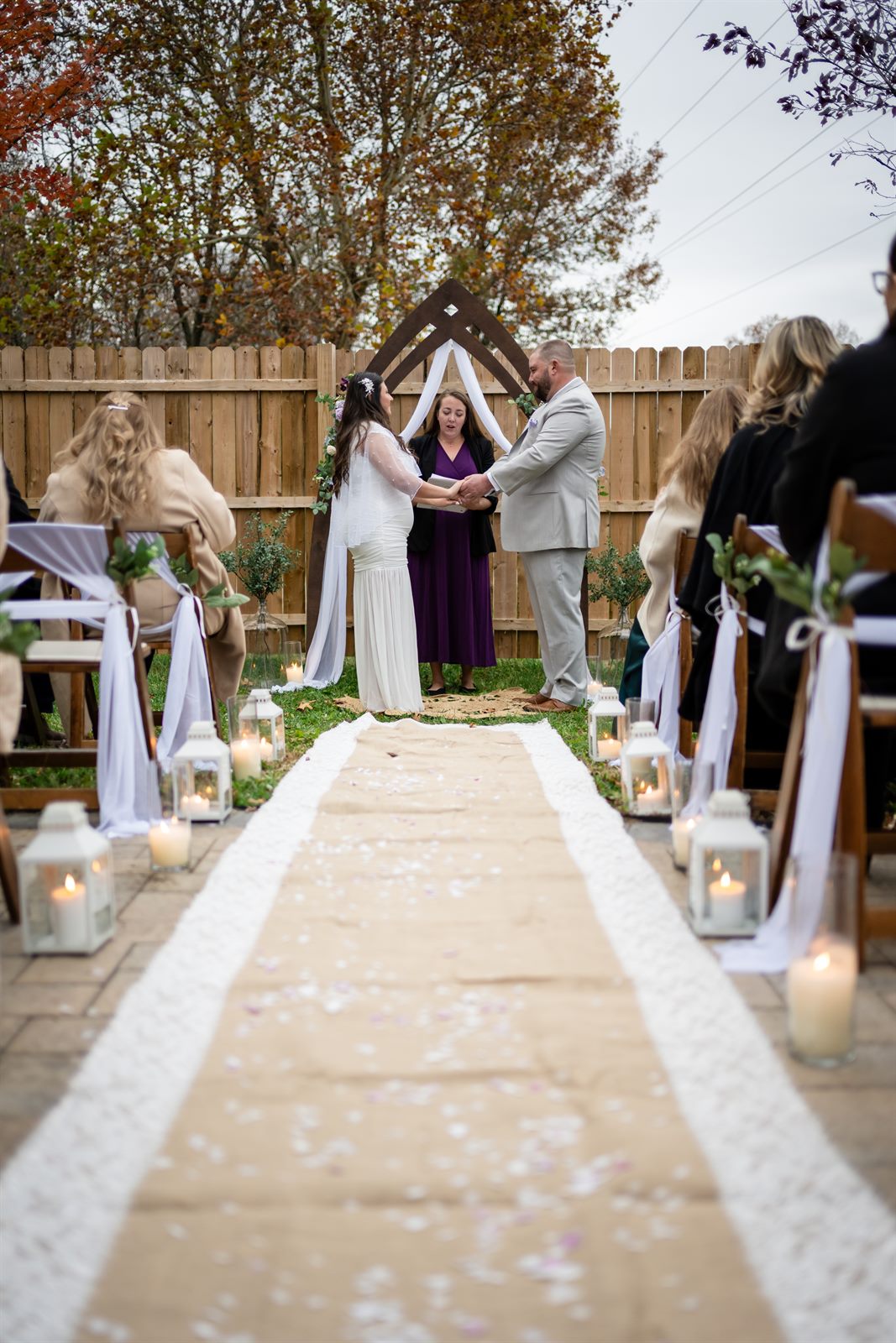 Intimate backyard wedding ceremony with a lantern-lined aisle