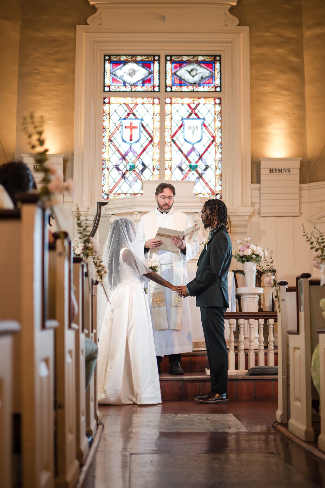 Couple exchanging vows beneath stained glass at a Philadelphia church wedding