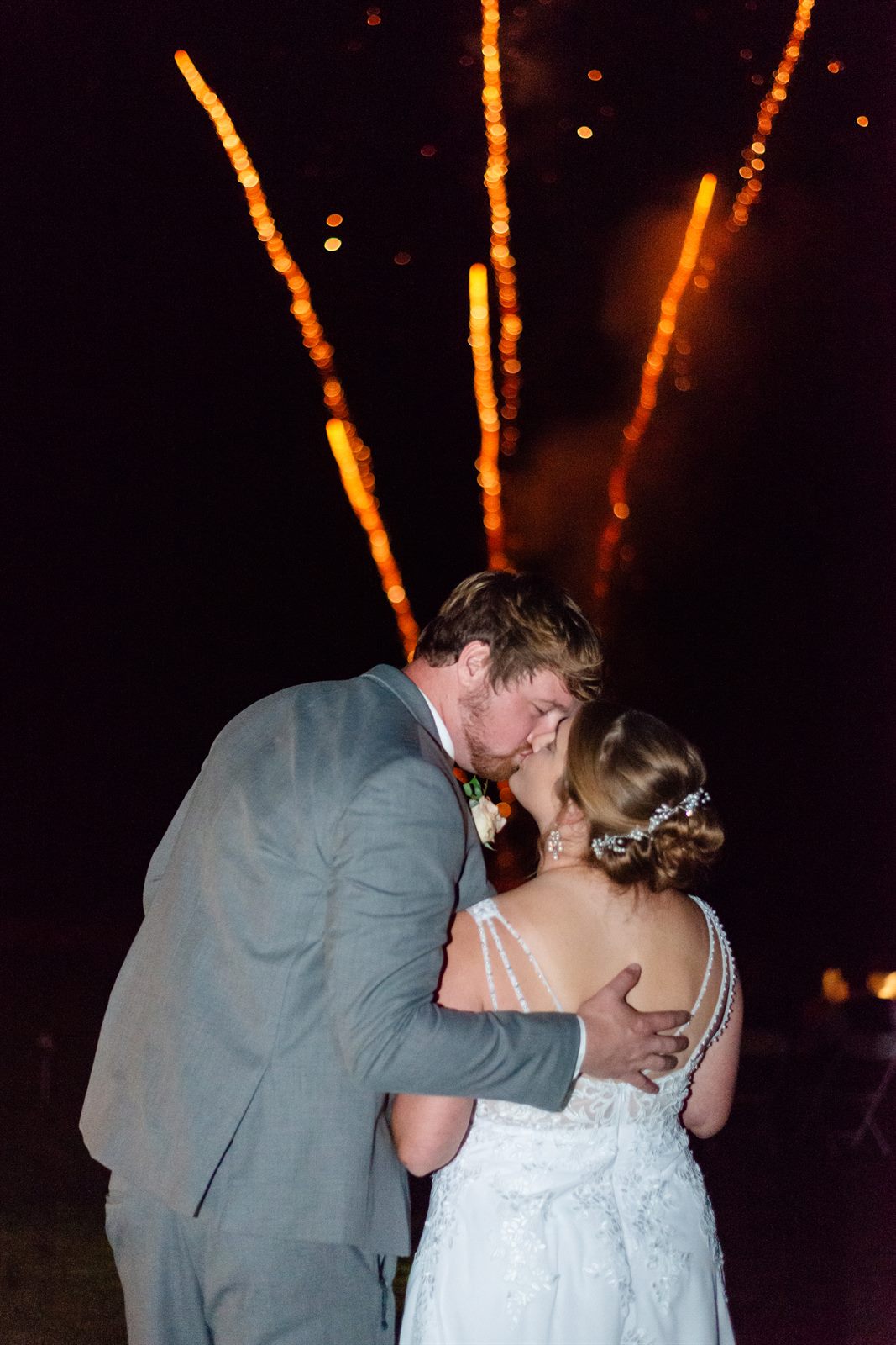 Couple kissing at night as fireworks go off behind them