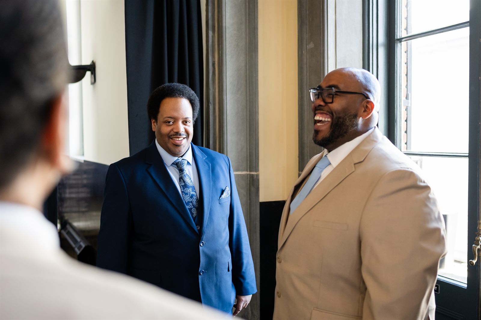 Two wedding guests laughing together before the ceremony