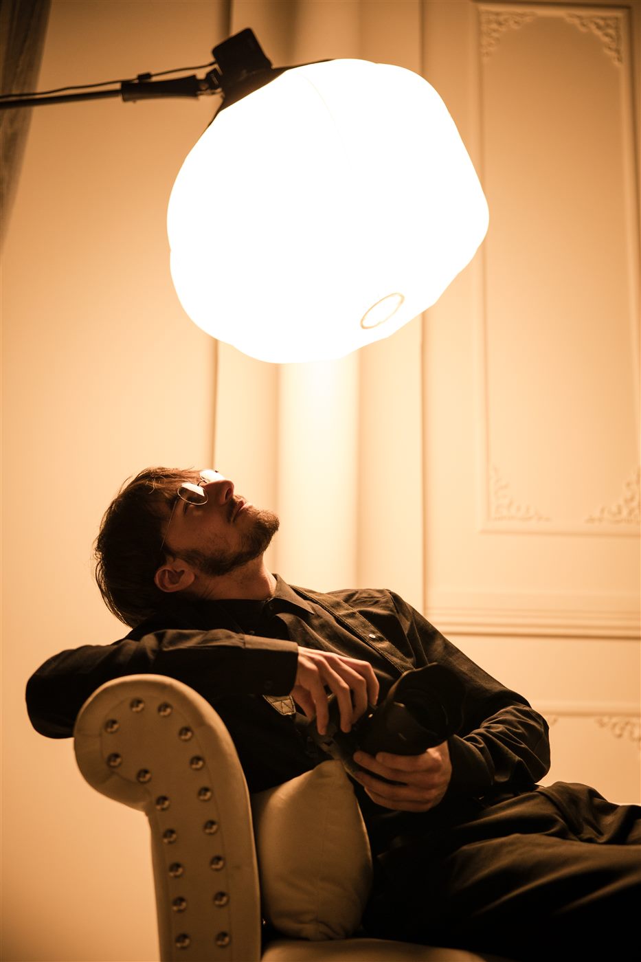 Nick relaxing under a studio light with his camera, between shots