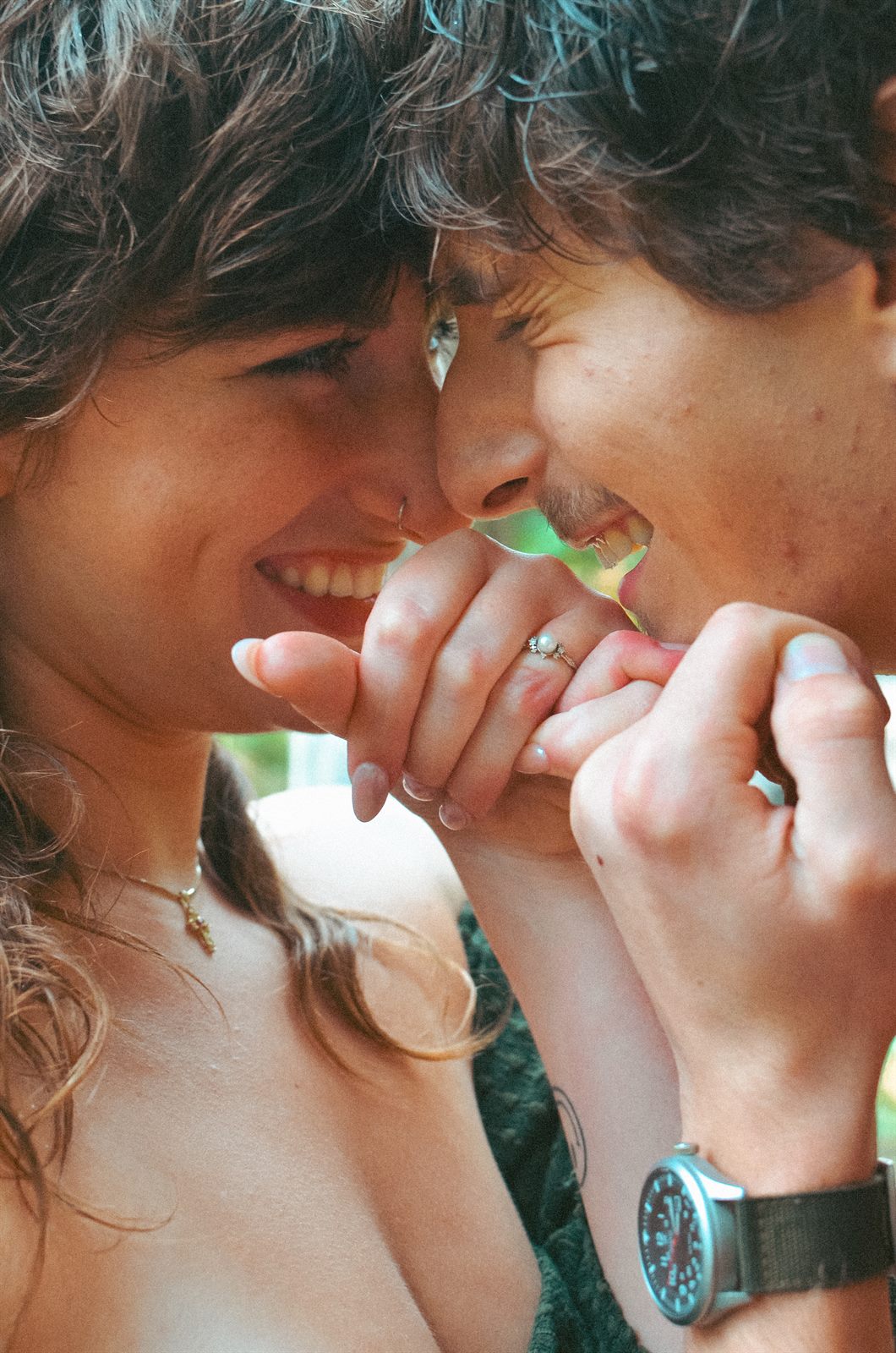 Close-up of a couple laughing while holding pinkies, engagement ring in view