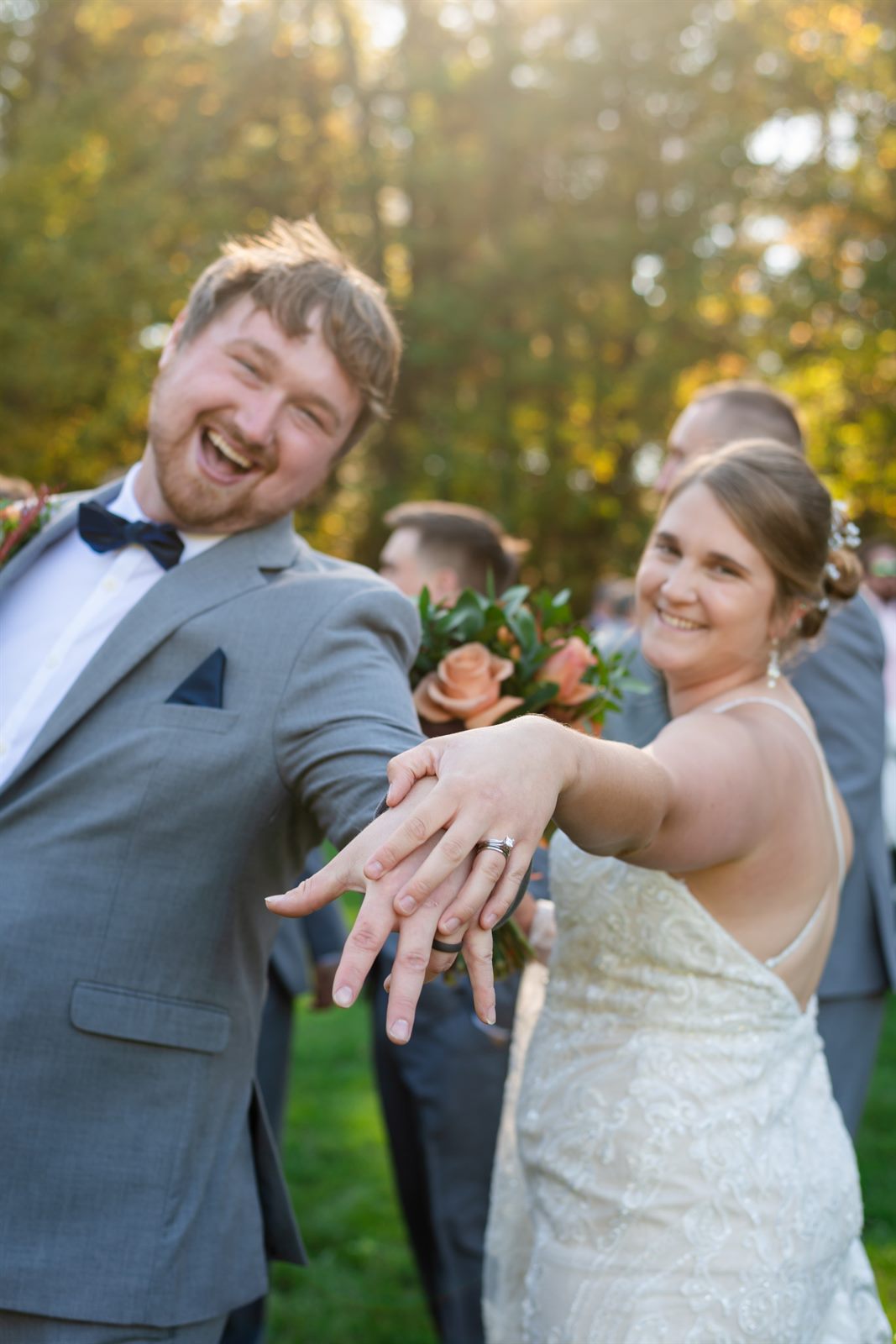 Bride showing off her ring while the groom celebrates at golden hour