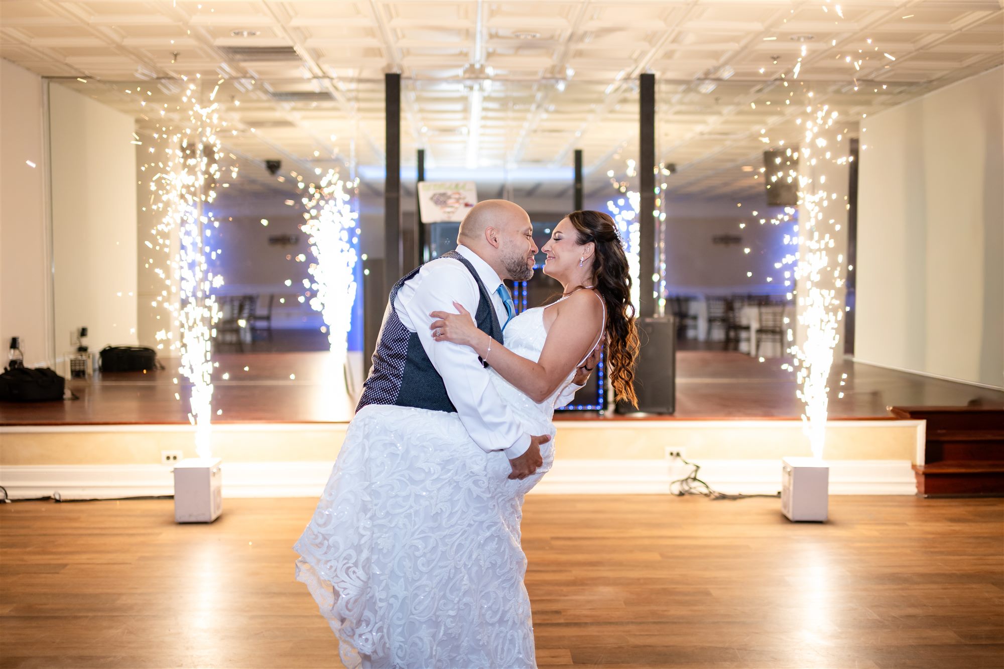 Groom dipping his bride for a kiss between cold spark fountains on the dance floor