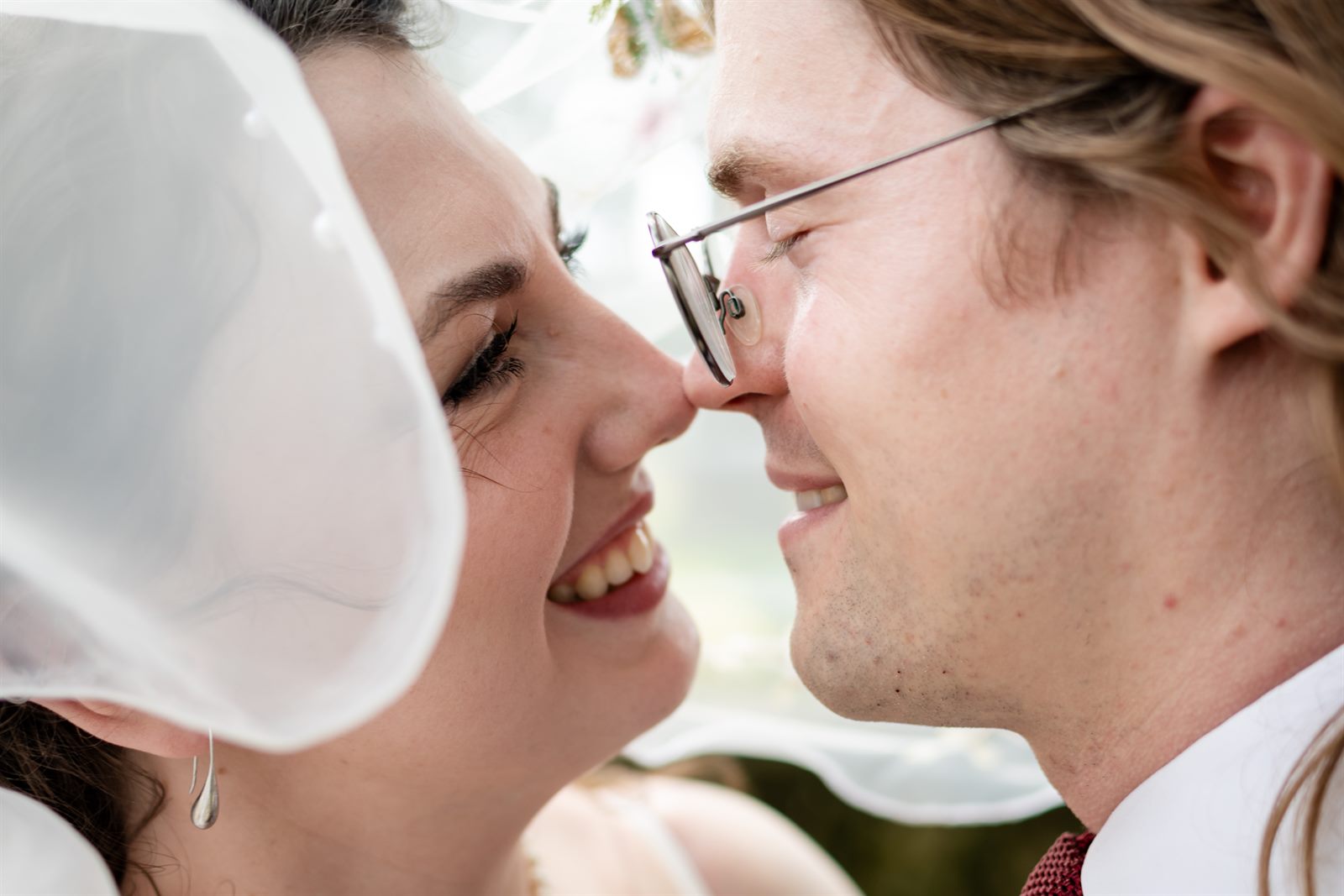 Bride and groom smiling under the veil, inches apart